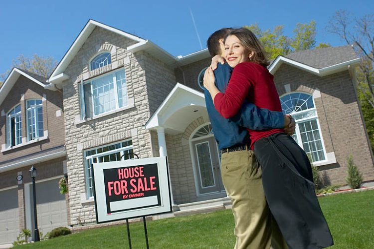 couple celebrating buying a house on the front lawn